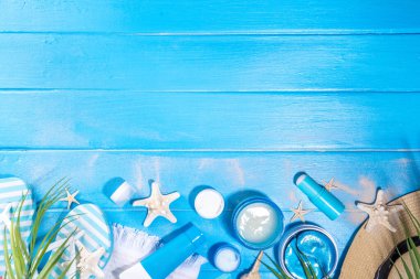 Summer skin care cosmetics set. Different jars, tubes of sunscreen moisturizer, cream, serum, masks, cosmetics for face and hands, on summer sea beach blue wooden background, accessorizes, seashells