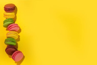 Parlak renkli (sarı, pembe, yeşil, kahverengi) çeşitli aromalı kurabiyeler, yüksek renkli arka planda tatlı kurabiyeler. Bir yığın küçük Fransız Makaronlu Kek, Boşluk Dizini Kopyala