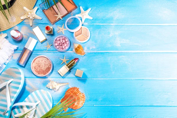 Summer make-up cosmetics flat lay, Vacation, Holiday shopping sale make up.Shadows, lipstick, mascara, face powder, blush on blue wooden background with summer accessories, starfish, shells