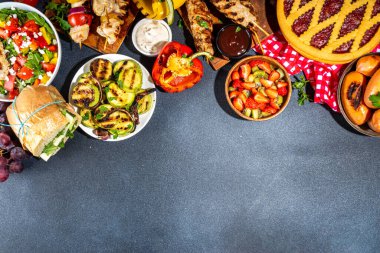 Çeşitli piknik barbekü yemekleri ve flatlay içiyorlar. Yaz bbq piknik yemekleri, ızgara etler, kebaplar, sebzeler, meyve salatası, geleneksel piknik pastası, sandviçler, üst görünüm fotokopi alanı.