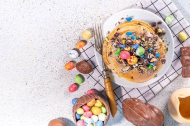 Paskalya için çocukların komik şirin kahvaltısı. Amerikan gözlemeleri, çikolatalı kızarmış hamur kekleri, çikolatalı yumurtalar, marşmelovlar, üzerine çikolata parçacıklı şeker serpiştirilmiş dekorlar.