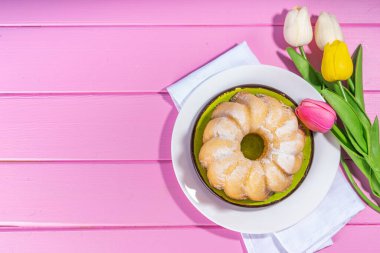 Geleneksel Paskalya yuvarlak pastası. Tatlı geleneksel Paskalya pişirmesi şeker tozu serpintileri, renkli Paskalya yumurtaları, bahar çiçekleri, pembe sarı renkli arka plan fotokopi alanı