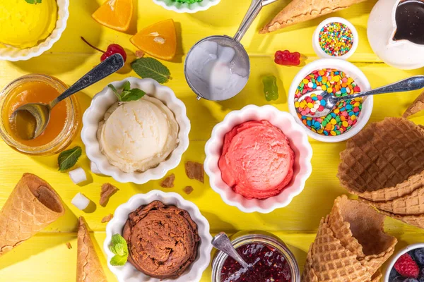 Ice cream festival background, Summer ice cream buffet with various gelato sundaes flavors. sweet toppings and sprinkles, high-colored yellow wooden background to view copy space