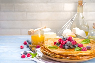 Rus Ukrayna Avrupa bayramı Maslenitsa. Geleneksel ince krep krepleri, böğürtlenli, reçelli ve bal soslu ahşap mavi masa, üst görünüm kopyalama alanı