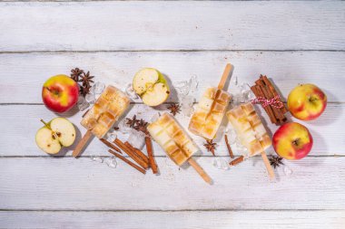 Elmalı turtalı dondurma çubuğun üzerinde. Elmalı turta aromalı ev yapımı lolipoplar, ahşap masa arkasında.