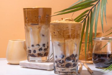 Boba dalgona kahvesi. Süslü Asya kahvesi, çırpılmış kahve ve tapyoka inci topları, güneşli arka planda yaz tatili köpüklü kokteyl bardağı.