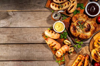 Bavyera sosisi, yuvarlak, gumberland, ketçaplı sucuk, hardal barbekü sosu. Çeşitli bbq ızgara sosisler ahşap arka planda yatıyordu. Sokak festivali ızgara yemek menüsü. 