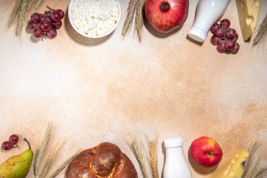 Mutlu Shavuot tebrik kartı geçmişi içinde Yahudi bayramının sembolleri olan - nar, üzüm, elma, tatlı challah ekmeği, buğday filizi, süt, peynir, süzme peynir, bej arka planda