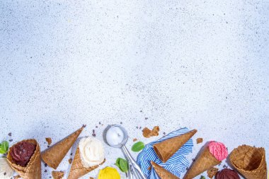 Waffle külahlarında parlak renkli dondurma koleksiyonu, beyaz beton arka planda çeşitli aromalı dondurma seti