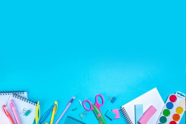 Düz bir zemin, parlak mavi arka planda renkli eğitim malzemeleri vardı. Okul konseptine geri dönelim. Okul çantasında makas, not defteri, kalem, kalem ve malzeme var. Üst görünüm, üstten kopyalama alanı