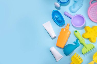 Bebek güneş kremi konsepti. Çocuklarla birlikte güneş kremi şişeleri tatil aksesuarları, kum kalıpları, panama şapkaları, açık mavi arka plan fotokopi alanı.