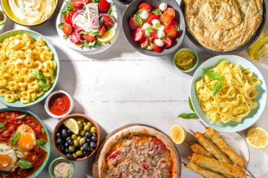 Farklı Akdeniz yemekleri: zeytin, mozarella domates salatası, Yunan salatası, makarna, tortellini ravioli, pizza, pita sandviçi, şiş kebap, shakshuka, humus, üst manzara