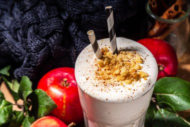Ev yapımı elmalı turta milkshake, tart parçacıkları ve baharatlı kırmızı sonbahar elma proteini smoothie, sıcacık ahşap arka planda mevsimlik sağlıklı bir kahvaltı içeceği.
