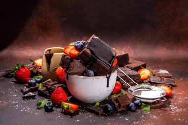 Böğürtlenli siyah çikolatalı kek. Üzerine çikolata sosu serpiştirilmiş ev yapımı kek kurabiyeleri ve koyu arkaplanda taze çilek, yabanmersini, fotokopi alanı.