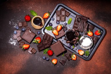 Böğürtlenli siyah çikolatalı kek. Üzerine çikolata sosu serpiştirilmiş ev yapımı kek kurabiyeleri ve koyu arkaplanda taze çilek, yabanmersini, fotokopi alanı.