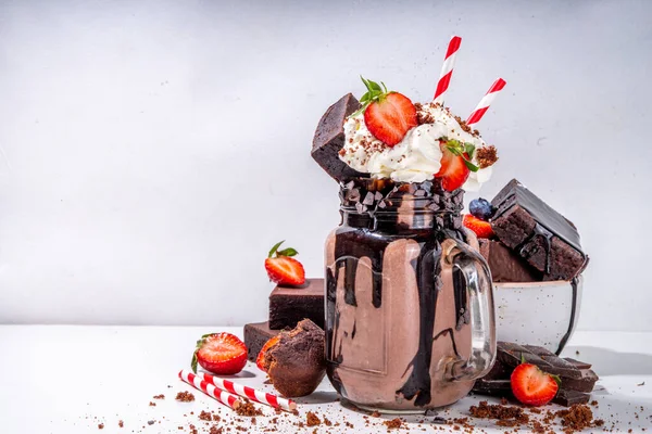 Double chocolate taste milkshake. Crazy shake with brownie taste, chocolate sauce, whipped cream topping and fresh strawberry, summer sweet loaded sweet dessert drink copy space