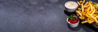 Ev yapımı patates kızartması ketçaplı ve mayonez soslu, siyah beton arka plan, kopyalama alanı.