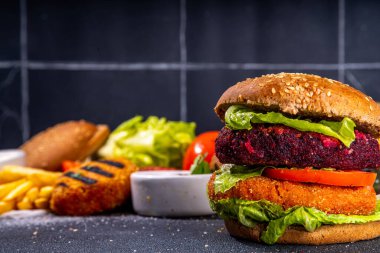 Sebze pirzolalı sağlıklı sebze burgerleri. Ev yapımı pancar kökü ve havuç burgeri, taze sebzeli, vegan mayonez soslu, tam tahıllı çörekler, koyu arkaplanda malzemeler, kopyalama alanı.