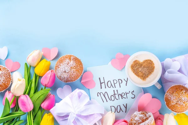 Mother's day holiday greeting card. Mother's Day morning breakfast with a cute surprise background, with gift boxes, cupcakes, coffee mug, heart decor, tulips and flowers, Happy Mother's Day letter