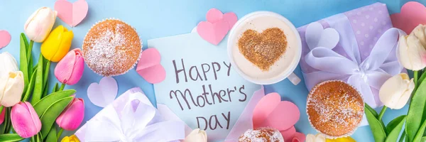 Mother\'s day holiday greeting card. Mother\'s Day morning breakfast with a cute surprise background, with gift boxes, cupcakes, coffee mug, heart decor, tulips and flowers, Happy Mother\'s Day letter