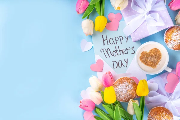 Mother's day holiday greeting card. Mother's Day morning breakfast with a cute surprise background, with gift boxes, cupcakes, coffee mug, heart decor, tulips and flowers, Happy Mother's Day letter