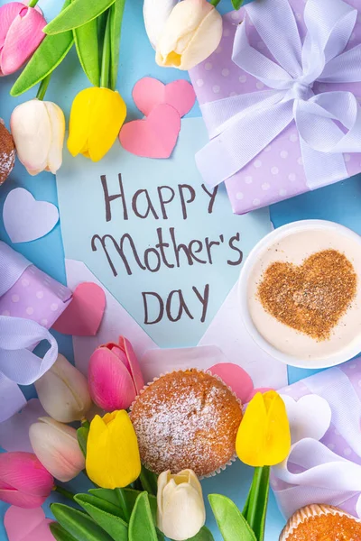 Mother\'s day holiday greeting card. Mother\'s Day morning breakfast with a cute surprise background, with gift boxes, cupcakes, coffee mug, heart decor, tulips and flowers, Happy Mother\'s Day letter