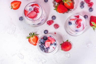 Alkolsüz yaz sütü kokteyli, sütsüz tatlı hindistan cevizi sütü moktail, taze çilek, yabanmersini, ahududu ve ezilmiş buz, parlak pembe arka planda.