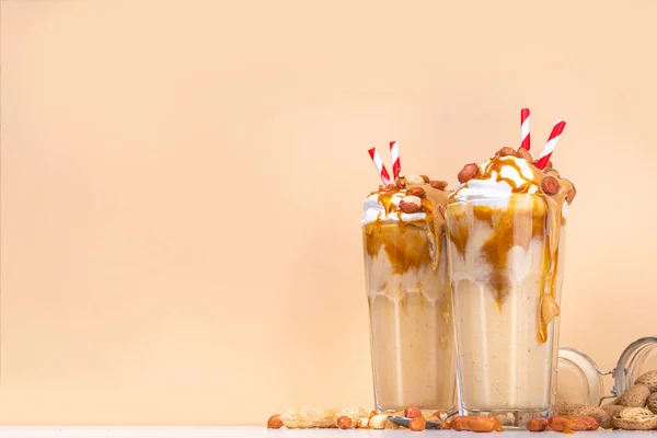 stock image Peanut butter smoothie, milk shake with a lot of peanuts and caramel sauce, beige background copy space