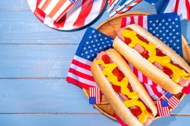 ABD Vatansever Piknik Tatil Sosislileri. Tahta tabakta Amerikan vatansever sosislisi ve Amerikan bayrağı. 4 Temmuz 'da Bağımsızlık Günü, Anma Günü veya Gaziler Günü