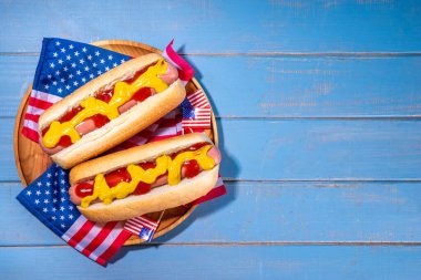 ABD Vatansever Piknik Tatil Sosislileri. Tahta tabakta Amerikan vatansever sosislisi ve Amerikan bayrağı. 4 Temmuz 'da Bağımsızlık Günü, Anma Günü veya Gaziler Günü