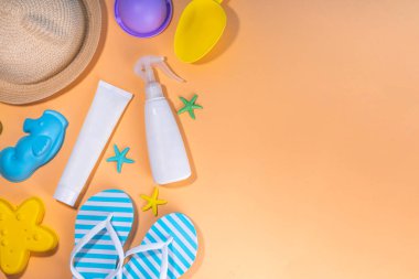 Çocuklar, çocuklar, bebek ve güneş koruması, UV korumalı güneş kremi kozmetikleri. Güneş kremi, güneş kremi, güneş gözlüğü, panama şapkası, kumlu bej arka planda oyuncaklar.