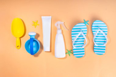 Çocuklar, çocuklar, bebek ve güneş koruması, UV korumalı güneş kremi kozmetikleri. Güneş kremi, güneş kremi, güneş gözlüğü, panama şapkası, kumlu bej arka planda oyuncaklar.