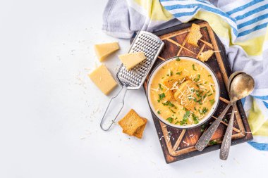 Homemade cheese cream soup, cheddar parmesan soup with croutons and greens, on white kitchen table background 