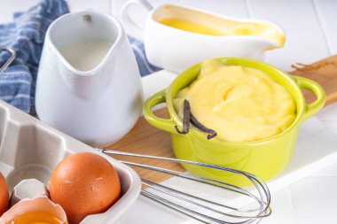 Malzemeli ev yapımı krema. Vanilya, süt ve yumurta. Tatlı krema beyaz mutfak masasının fotokopi masasında tatlı pişirme arkaplanı. 