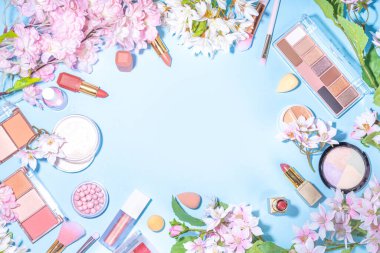 Spring make up set on light blue background. Different make-up professional cosmetics, beauty accessories flat lay with spring blossom flowers top view copy space clipart