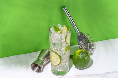 Klasik yaz soğuk mojito kokteyli, limonlu limonata, nane, ezilmiş buz ve beyaz arka planda bar aletleri.