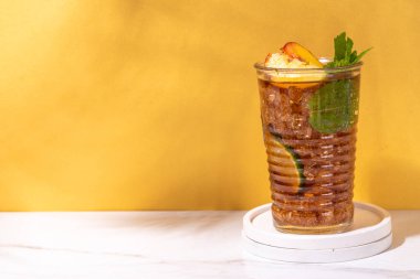 Buzlu şeftali çayı, ya da limonlu şeftali limonatası, nane, ezilmiş buz ve altın bej arka planda bar aletleri. 