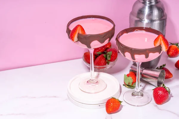 Sweet chocolate strawberry cocktail, cute pink strawberry martini or daiquiri creamy drink, with fresh strawberry garnish and choco drizzles, on high-colored pink background