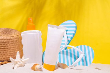 Kumsalda güneş kremi şişeleri, elektrik sarısı arka plan. Yüksek renkli yaz sağlığı ve cilt bakımı geçmişi, güneş kremi kremi. Güneş, Uv cilt bakımını koruyan güneş kremi kozmetik ürünleri