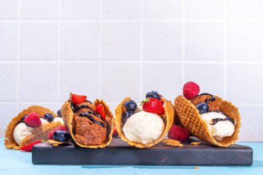 Çeşitli tatlı taco dondurmaları. Çikolata ve vanilya aromalı waffle kabukları. Farklı meyveler, meyveler, malzemeler.