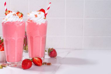 Rubarb ve çilekli milkshake veya smoothie, ferahlatıcı yaz içeceği, sağlıklı diyet ve antioksidan yaz içeceği kremalı, taze ravent, çilek dilimleri, beyaz mutfak masasında.