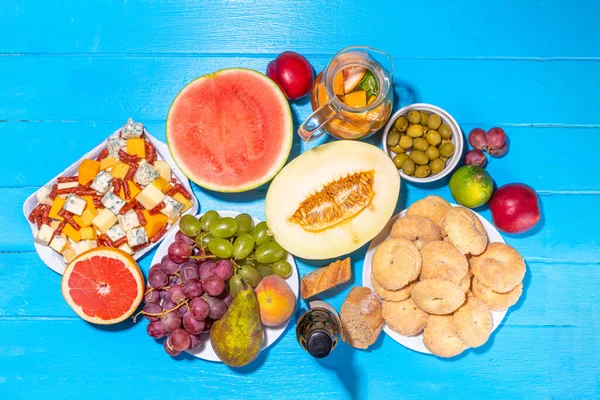 Buon Ferragosto (happy in italian language) holiday background. Summer Italian harvest festival August 15  brunch, family party antipasto foods with watermelon, melon, grapes, cheese, snacks, drinks