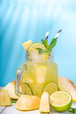 Kavun limonata ya da mojito, kavun ve limon suyu, ezilmiş buzla, nane yapraklarıyla süslenmiş meyve dilimleri. Taze organik yaz içeceği, meyveli su moktail 'i, yüksek renkli güneşli arka planda. 