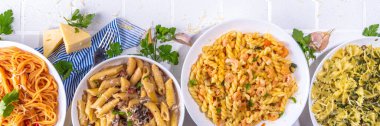 Beyaz fayanslı arka planda farklı soslu makarna seti. Spagetti, farfalle, makarna, deniz ürünleri, ıspanak, karbonara, domates soslu fusilli makarna. İtalyan yemeği, Akdeniz yemeği konsepti
