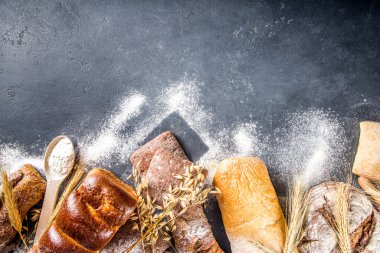 Çeşitli ekmek setleri. Birçok farklı buğday, tahıl ve çavdar ekmeği çavdar ve buğday, un ve fırıncı aletleriyle beyaz ahşap arka planda.