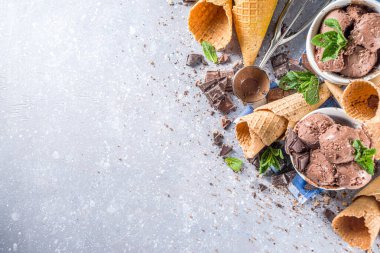 Ev yapımı çikolatalı dondurma, çikolata parçaları, talaş ve dondurma külahları. Beyaz gri taş masa üzerindeki küçük beyaz kaselerde fotokopi alanı