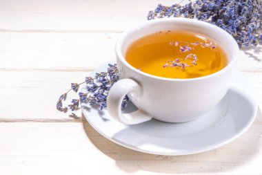 Organik lavantalı çay fincanı. Taze lavanta çiçekli sıcak bitkisel çay, beyaz seramik bardakta ahşap arka planda fotokopi alanı