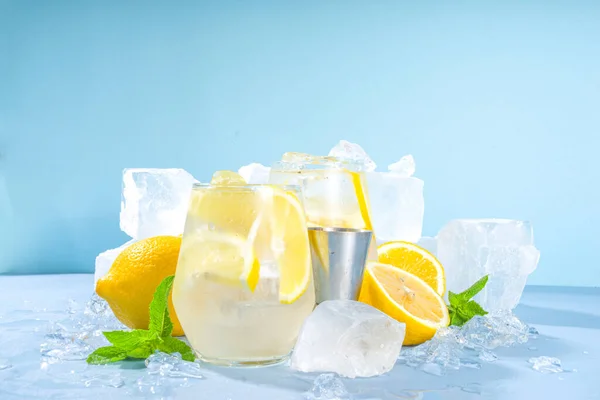 伝統的な夏の冷たいさわやかなカクテルレモネード レモンスライスと青の背景に砕いた氷と氷の台座の多く — ストック写真