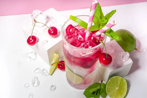 冷たくてさわやかな夏の飲み物 チェリーコーラ リメイド モヒートレモネードカクテルライムとチェリーのカラフルな明るいピンクの背景 — ストック写真