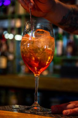 Gerçekçi fotoğraf, bardaki profesyonel barmenin buzlu ve alkollü kokteyl yaparken çekilmiş yakın plan fotoğrafı.